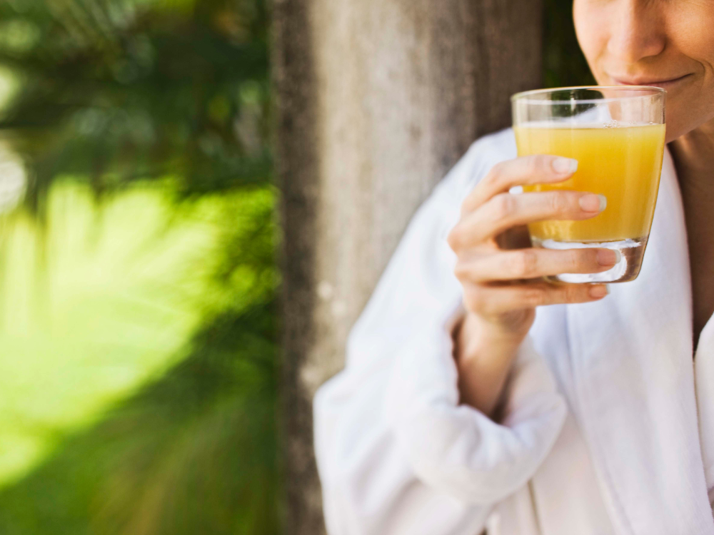 Mulher segurando suco natural, uma opção leve e refrescante indicada em o que comer depois da endoscopia.