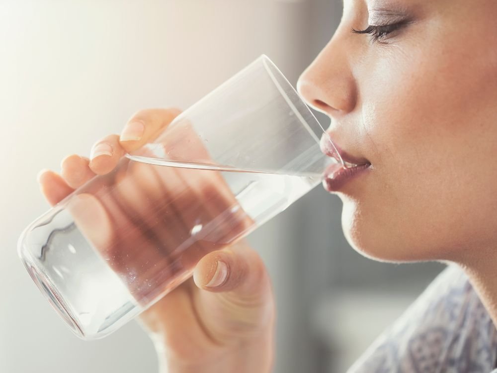 Mulher bebendo água. A ingestão de água antes do exame gera dúvidas comuns, como se jejum para endoscopia pode beber água com antecedência.