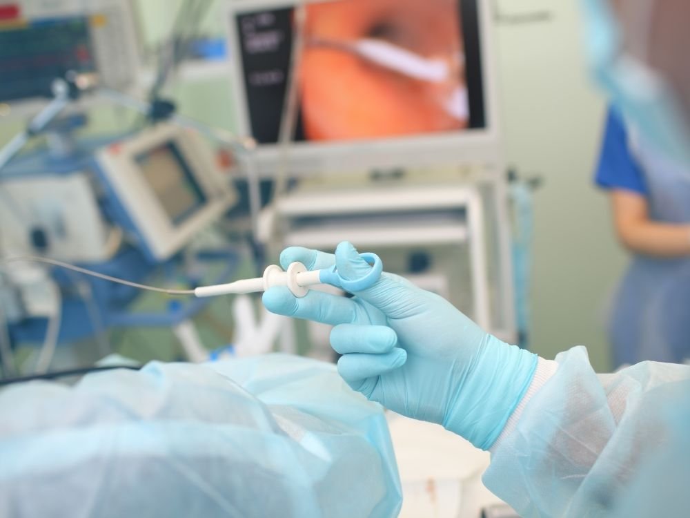 Médico segurando instrumento durante exame endoscópico, com monitor exibindo imagem interna. O resultado da endoscopia sai na hora dependendo da análise.