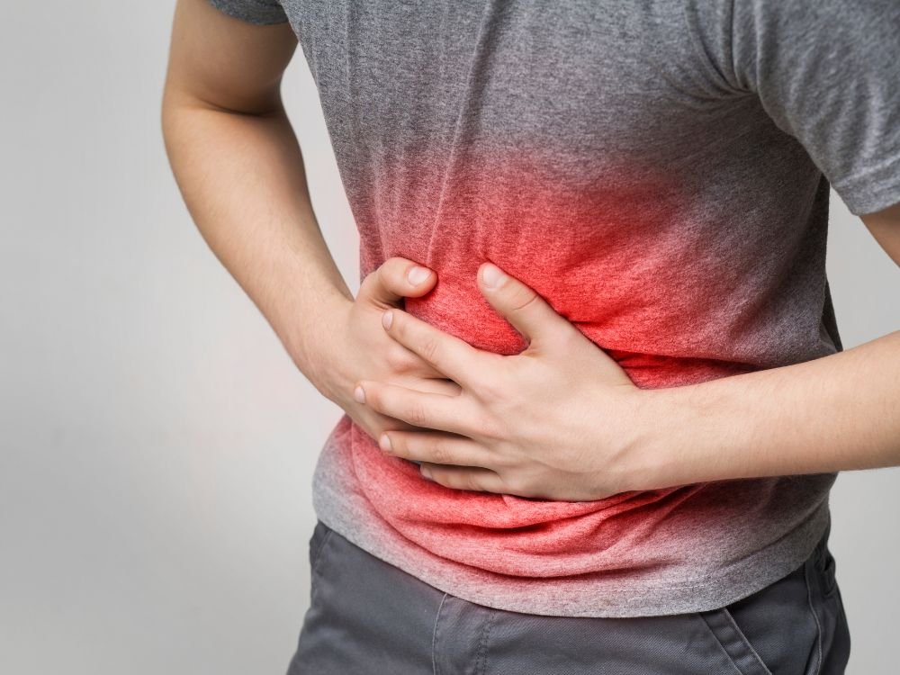 Homem com dor abdominal intensa segurando o abdômen, indicando sintomas comuns da SIBO como inchaço e gases.
