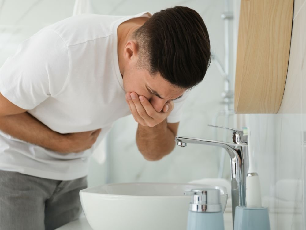 Homem com náusea no banheiro, uma das manifestações do supercrescimento bacteriano do intestino delgado (SIBO).