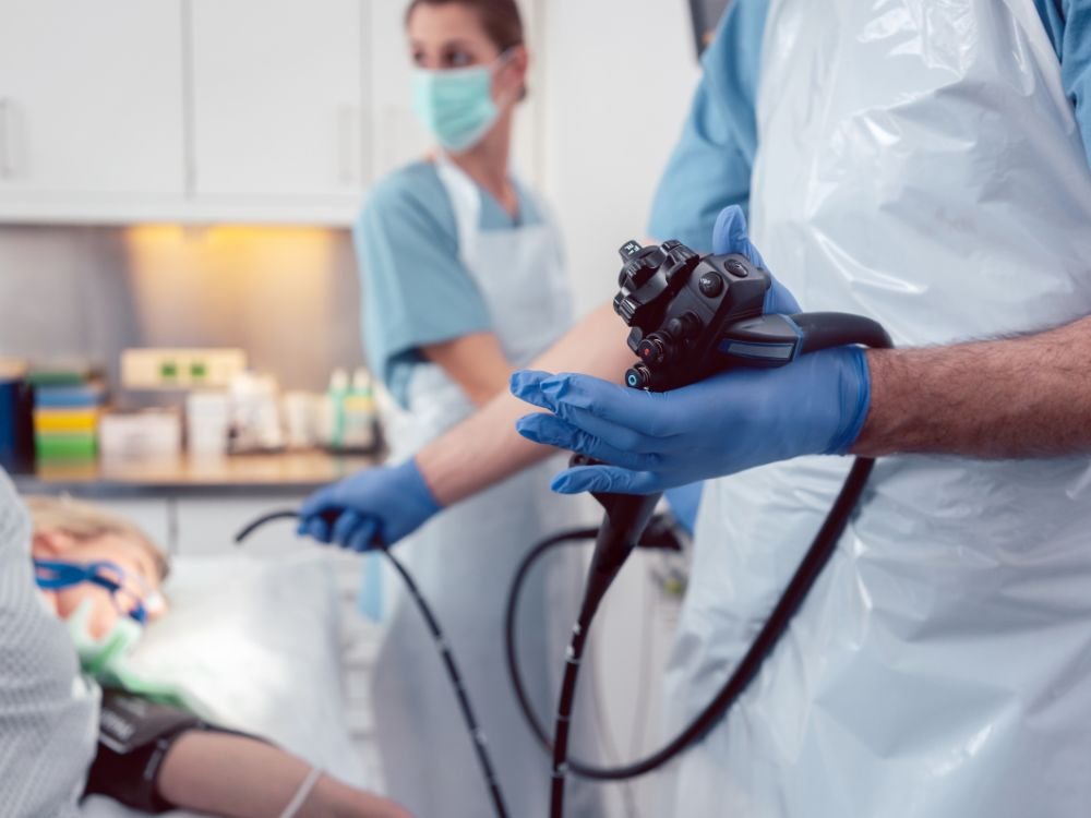Equipe médica conduzindo exame com paciente sedado e monitorado, mostrando estrutura adequada que minimiza os riscos da endoscopia.