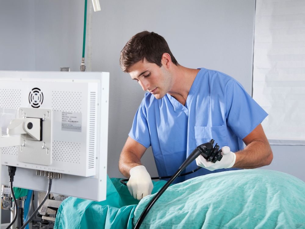 Médico realizando procedimento endoscópico com monitor, mostrando etapa do processo de gastroplastia endoscópica para emagrecimento.