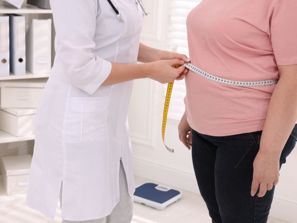 Médica medindo a circunferência abdominal de paciente com sobrepeso em consulta para avaliação de balão gástrico.