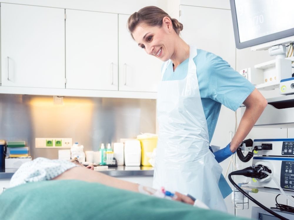 Equipe médica acompanhando paciente em sala de exame, reforçando a etapa clínica e o cuidado envolvidos no preparatório para endoscopia.