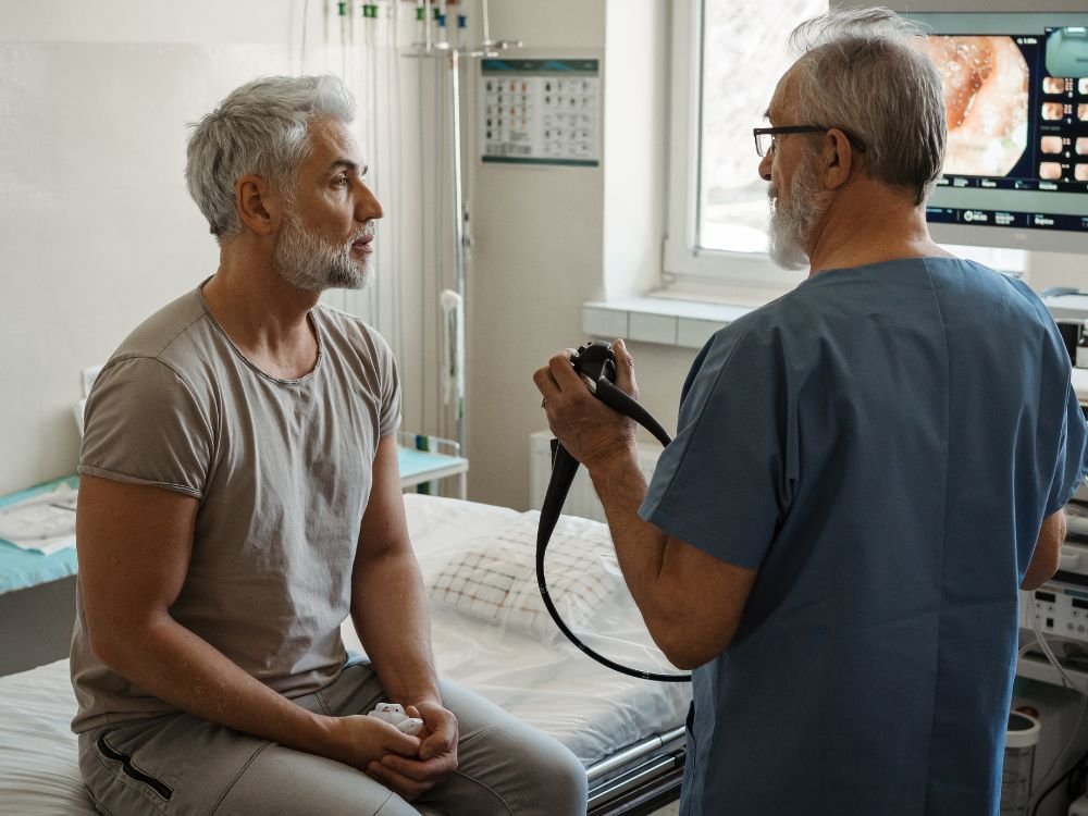 Paciente em consulta com médico antes do exame, explicação detalhada sobre como é feita a colonoscopia e orientações pré-procedimento.