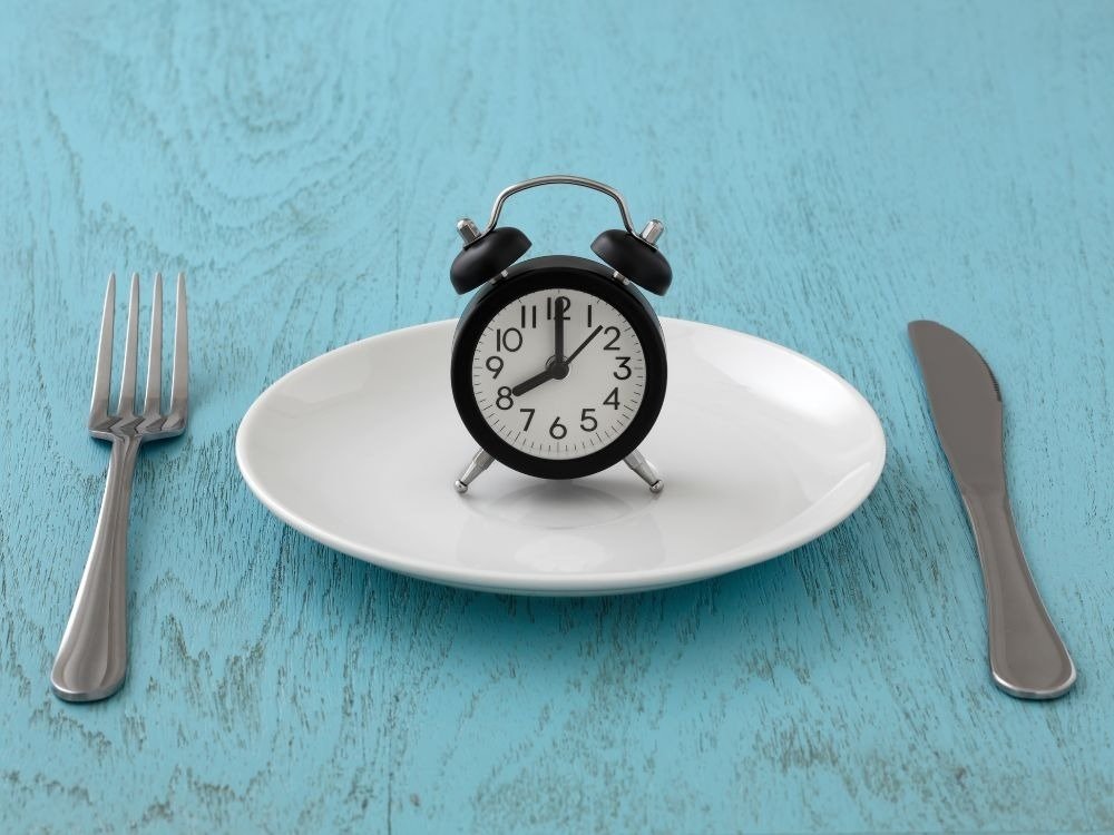 Relógio sobre prato simbolizando a importância do tempo de jejum para endoscopia antes do exame.