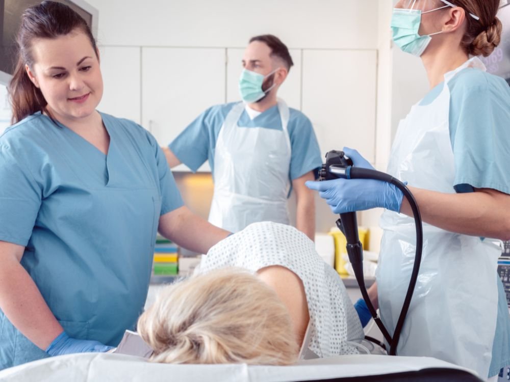 Equipe médica posicionando o paciente na sala de exames durante o procedimento de como é feita a colonoscopia.