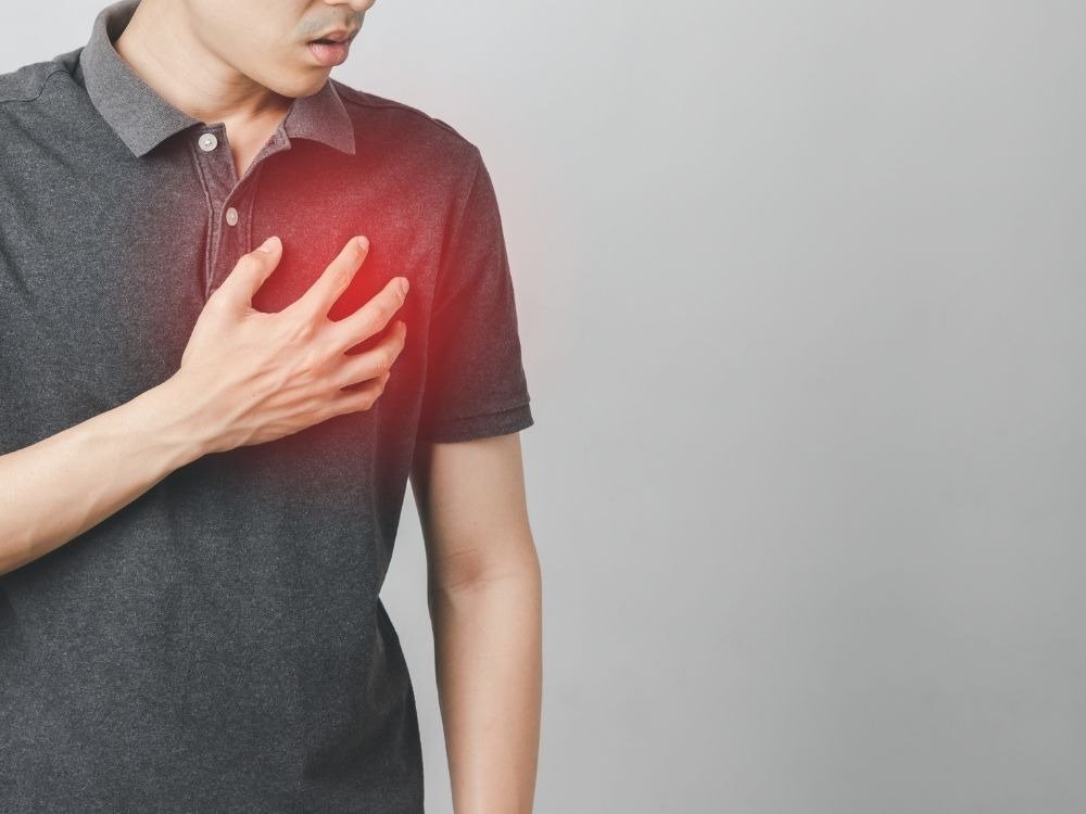 Homem com dor no peito representando preocupação cardíaca e a dúvida sobre quem tem arritmia pode fazer endoscopia.