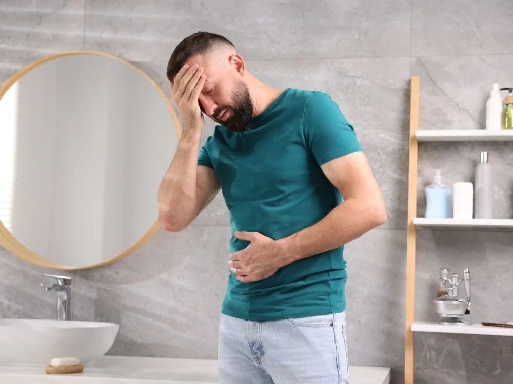 Homem com dor abdominal e expressão de desconforto, ilustrando dúvidas comuns sobre se endoscopia dói durante o exame digestivo.