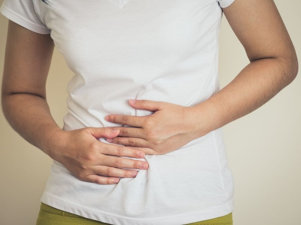 Desconforto abdominal associado à queimação no estômago com mãos pressionando a região do abdômen