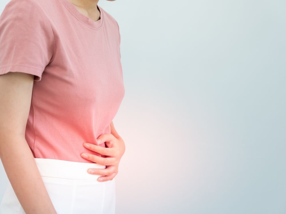 Pessoa com dor abdominal e queimação, quadro comum de refluxo em adultos ligado à irritação causada pelo ácido gástrico.