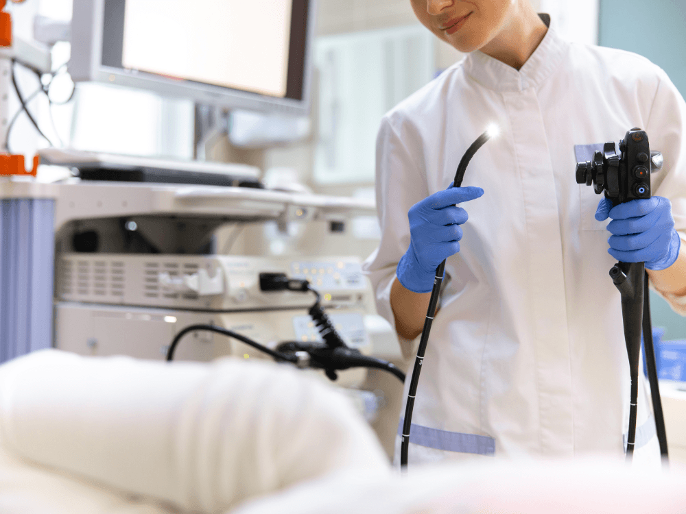 Profissional de saúde segura um endoscópio antes do exame, destacando os equipamentos utilizados durante a endoscopia com sedação.