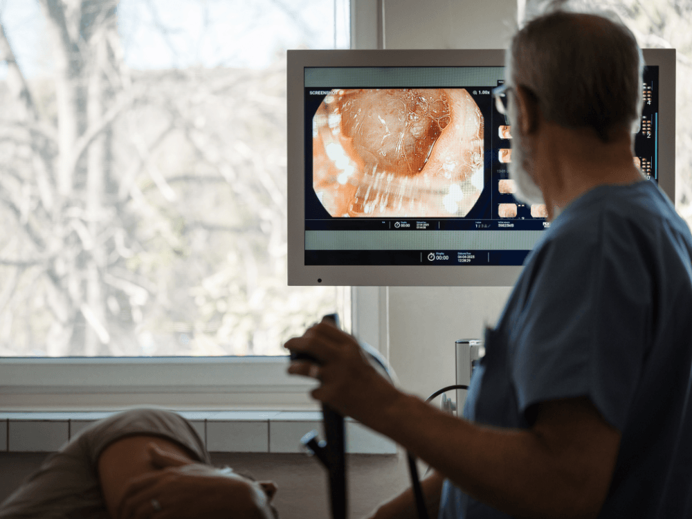 Profissional observa as imagens exibidas no monitor durante uma endoscopia para acompanhar o exame realizado sob sedação.