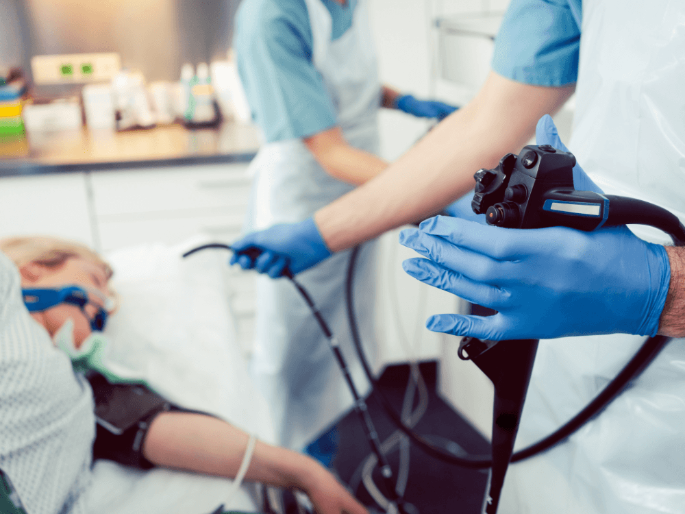 Equipe médica prepara o endoscópio enquanto o paciente permanece deitado para realizar o exame, mostrando quanto tempo dura a sedação da endoscopia