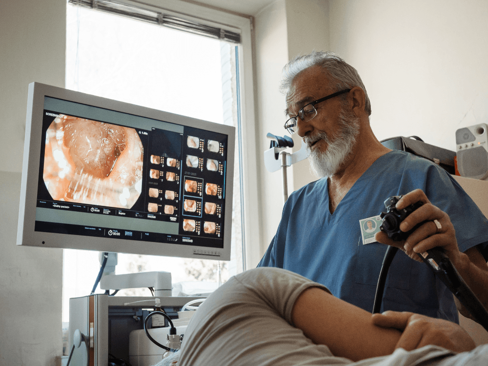 Médico realiza exame de endoscopia digestiva enquanto acompanha as imagens do procedimento em um monitor durante a sedação.