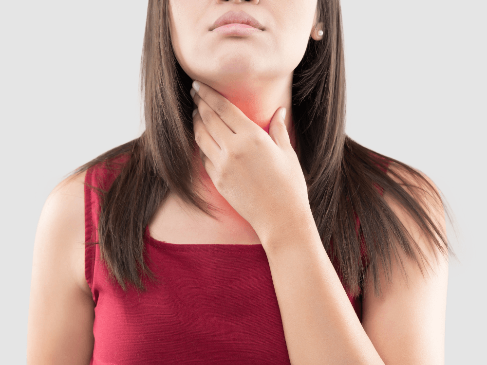 Pessoa toca a região da garganta com expressão de desconforto, ilustrando irritação frequentemente relacionada ao refluxo gastroesofágico.