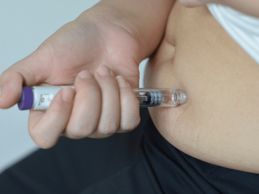 Pessoa aplica uma caneta emagrecedora por injeção na região da coxa, ilustrando a administração de medicamentos para perda de peso. Tudo para explicar os canetas emagrecedoras efeitos colaterais