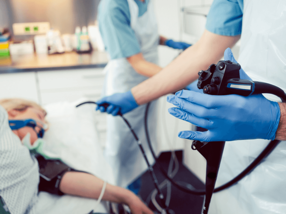 Profissional de saúde realiza exame endoscópico em paciente, procedimento usado para avaliar o trato digestivo e investigar alterações gástricas.