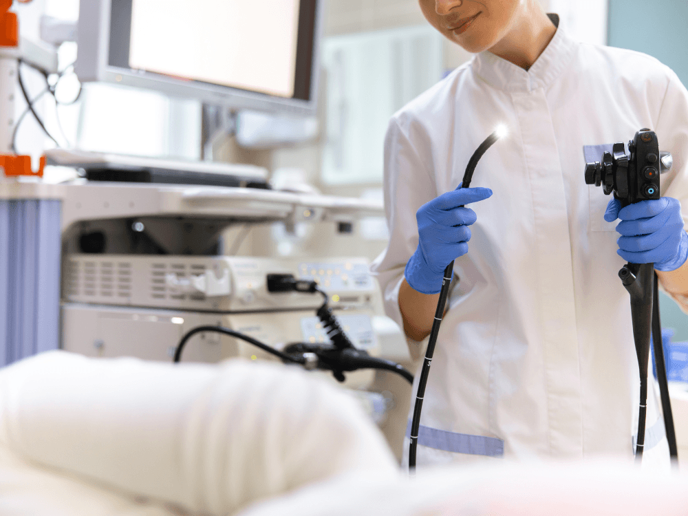 Profissional de saúde segura um aparelho de endoscopia durante exame do sistema digestivo em ambiente hospitalar. Tudo para explicar sobre os sintomas após endoscopia com biópsia.